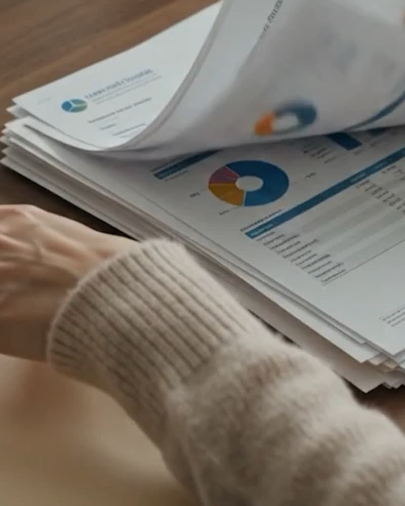 A stack of printed reports with charts being turned over